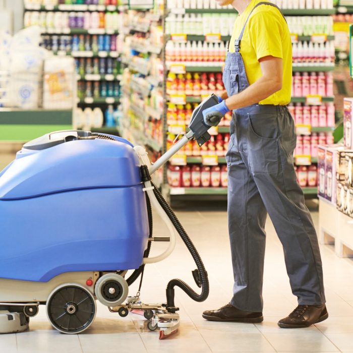 worker cleaning store floor with machine Floor care and cleaning services with washing machine in supermarket shop store
